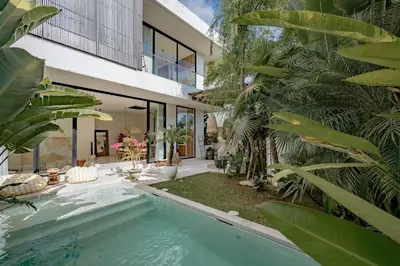 an indoor swimming pool in a house with palm trees at Casa Noema in Kerobokan
