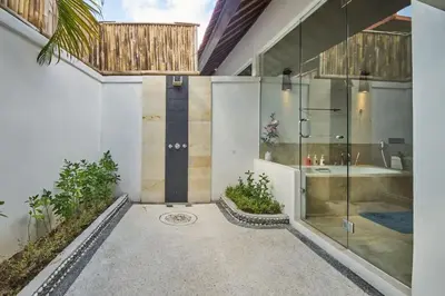 a bathroom with a glass shower and a tub at Villa Bulan Batubelig in Canggu