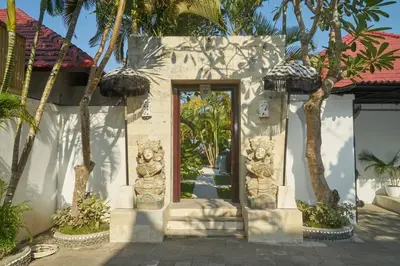 a white building with a door with palm trees at Villa Bulan Batubelig in Canggu