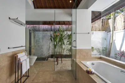 a bathroom with a tub and a glass shower at Villa Bulan Batubelig in Canggu