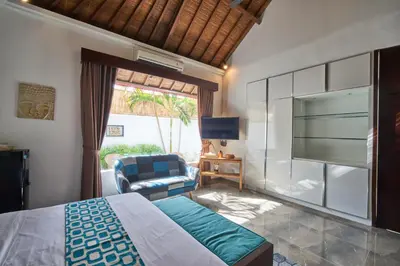 a bedroom with a bed and a chair and a television at Villa Bulan Batubelig in Canggu