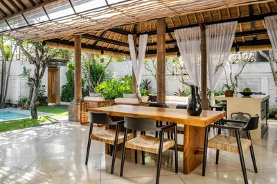 an outdoor dining area with a wooden table and chairs at Rumah Ananda Bali - Balinese Villa Umalas in Canggu