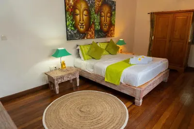 a bedroom with a bed with a painting of two faces at Shray Villa. Legian in Legian