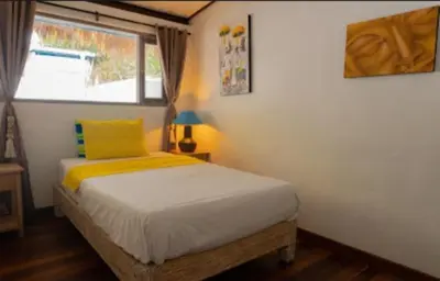a bedroom with a bed with a yellow pillow and a window at Shray Villa. Legian in Legian