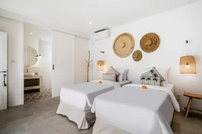 two beds in a white room with a bathroom at Villa Cyma by Alfred in Bali in Seminyak