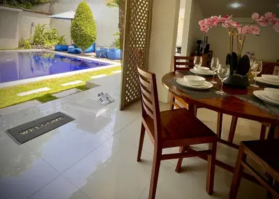 a dining room with a table and a swimming pool at Villa Majegau 1 Seminyak in Seminyak