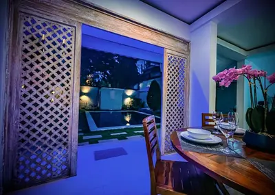 a dining room with a wooden table and a lattice door at Villa Majegau 1 Seminyak in Seminyak