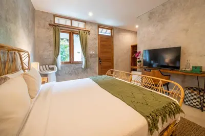 a bedroom with a large bed and a television at Little Boutique Hotel 107- 30m from beach in Canggu