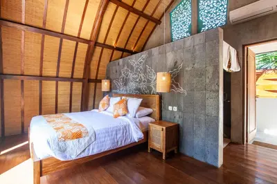 a bedroom with a bed and a wall with windows at Sunset Paradise Villa Nusa Dua in Nusa Dua