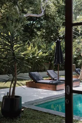 a pool with two chaise lounges next to a palm tree at Villa Amara Pradi - 550m to Petitenget Beach in Seminyak