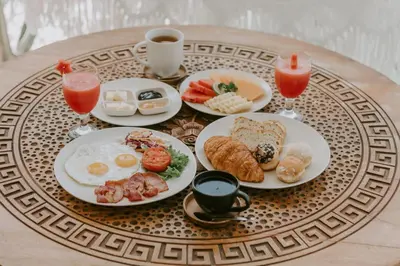 a table topped with plates of breakfast foods and drinks at Villa Amara Pradi - 550m to Petitenget Beach in Seminyak