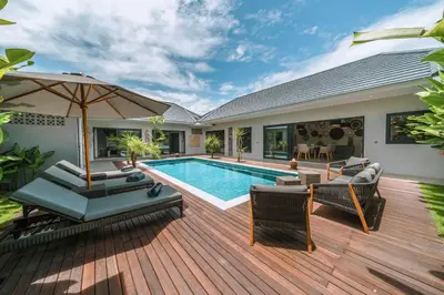 a backyard with a swimming pool and a wooden deck at Villa Batik - Brand New & Stylish 3BR Villa in Seminyak! in Seminyak