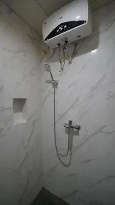 a shower in a bathroom with a white marble wall at Maharani Residence in Denpasar