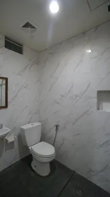 a white bathroom with a toilet and a sink at Maharani Residence in Denpasar