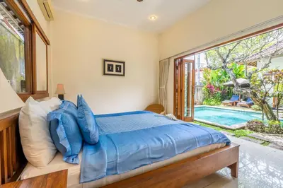 a bedroom with a bed with blue pillows and a pool at Taman Rahasia by iBali Management in Kerobokan