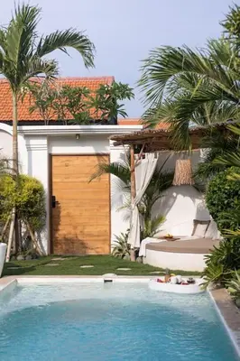a swimming pool in front of a house with palm trees at Villa Kanopi Luxurious 3BR Villa with Pool and Quick Beach Access in Canggu