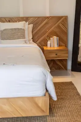 a bed with a wooden headboard and a night stand at Villa Kanopi Luxurious 3BR Villa with Pool and Quick Beach Access in Canggu