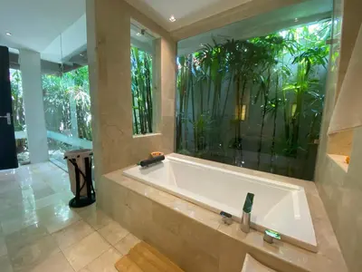 a bath tub in a bathroom with a large window at Lotus Luxury Villa Seminyak in Seminyak