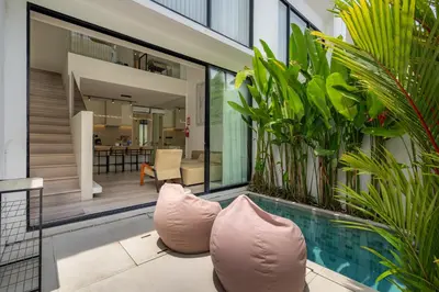a swimming pool with two pink pillows next to a house at Oasis Villa 8 by Betterplace in Canggu