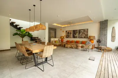 a living room with a table and chairs and a couch at Flores Villa by Betterplace in Canggu