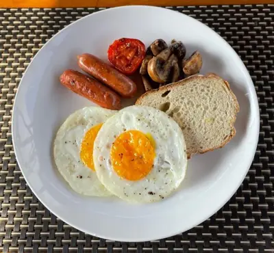 a plate of breakfast food with eggs sausage and bread at Kos Bulan Bali in Kuta