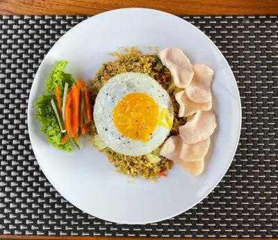 a plate of food with an egg and vegetables at Kos Bulan Bali in Kuta