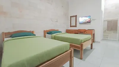 a room with two beds and a tv on a wall at Kos Bulan Bali in Kuta