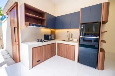 a kitchen with blue cabinets and a refrigerator at Villa Kamandari in Kuta