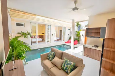 a living room with a couch and a swimming pool at Villa Kamandari in Kuta