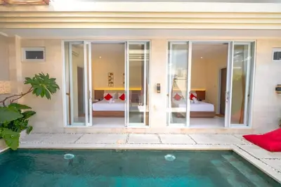 a villa with a swimming pool and a bedroom at Villa Kamandari in Kuta