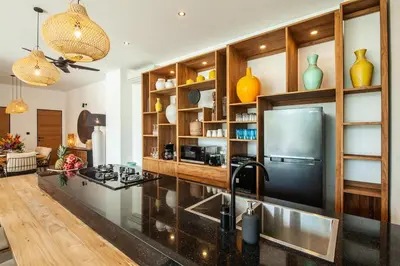 a kitchen with a black counter top and wooden cabinets at Zayana Villas Resort Seminyak in Seminyak