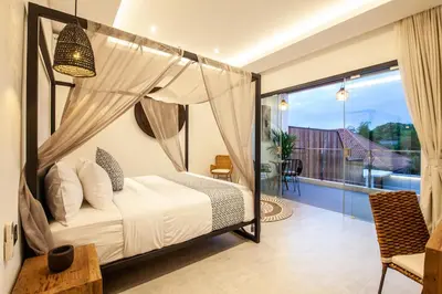 a bedroom with a canopy bed and a balcony at Zayana Villas Resort Seminyak in Seminyak