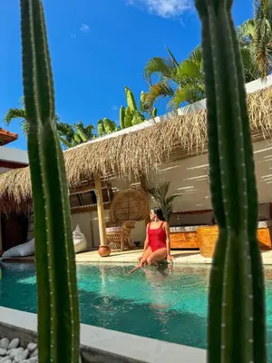 a woman sitting in a swimming pool next to a cactus at Villa Anoli - 3 chambres - Centre de Seminyak in Seminyak