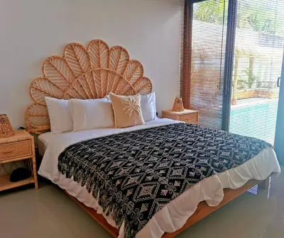 a large bed with a large headboard in a bedroom at Villa Anoli - 3 chambres - Centre de Seminyak in Seminyak