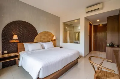 a bedroom with a large white bed and a chair at Cove Tevana in Seminyak