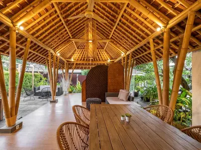 an outdoor dining area with a wooden table and chairs at Cove Tevana in Seminyak