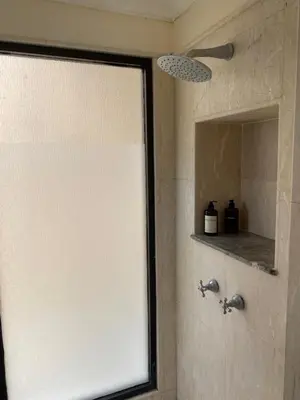 a bathroom with a shower with a mirror at Jimbaran BeachStroll Villa (2BR) in Jimbaran