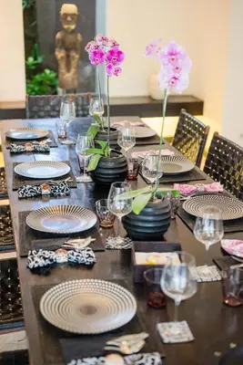 a table with plates and glasses and flowers on it at Villa Spirit 4 BR - Canggu in Canggu
