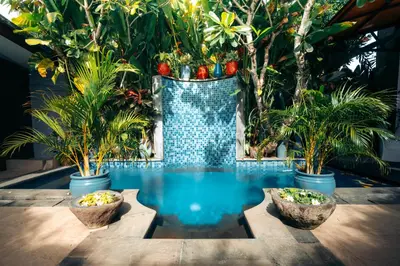 a pool with three potted plants and a large vase at Bali Adua Villa in Seminyak