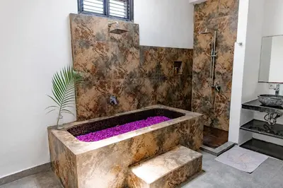a bathroom with a large stone tub with purple flowers at Saga Villas Oasis in Seminyak