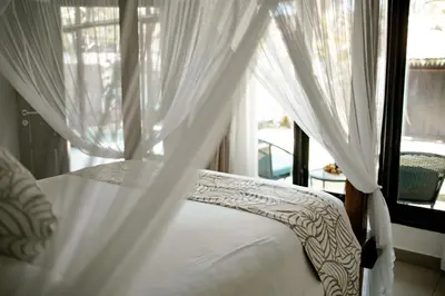 a bedroom with a bed with white curtains and a window at Saga Villas Oasis in Seminyak