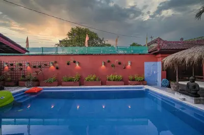 a swimming pool in front of a red wall at Huge 2 Bedroom private pool Villa - Gong Zhu Camille in Pesanggaran
