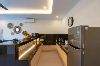 a kitchen with a refrigerator and a clock on the wall at Vast 5bd Villa with Garden and Private Pool 250m to Beach in Seminyak