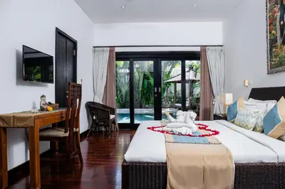 a bedroom with a bed and a table and a desk at Cempaka Villa by Premier Hospitality Asia in Nusa Dua