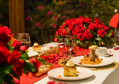 a table topped with plates of food and red roses at Cempaka Villa by Premier Hospitality Asia in Nusa Dua