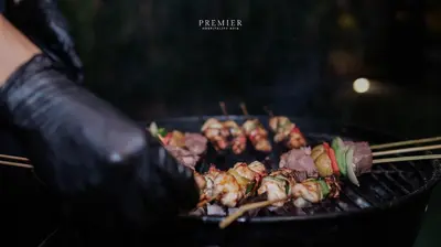 a person is cooking food on a grill at Cempaka Villa by Premier Hospitality Asia in Nusa Dua