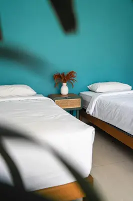 two beds in a room with a blue wall at SHAKA CLAN SURF in Canggu