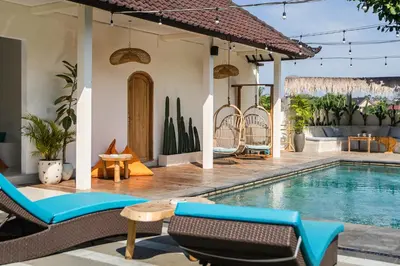a house with a swimming pool with chairs and a table at SHAKA CLAN SURF in Canggu