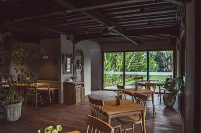 a restaurant with tables and chairs and a large window at White Penny Hostel in Seminyak