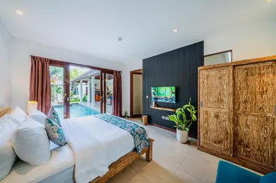 a bedroom with a large bed and a tv at Villa Olli in Seminyak